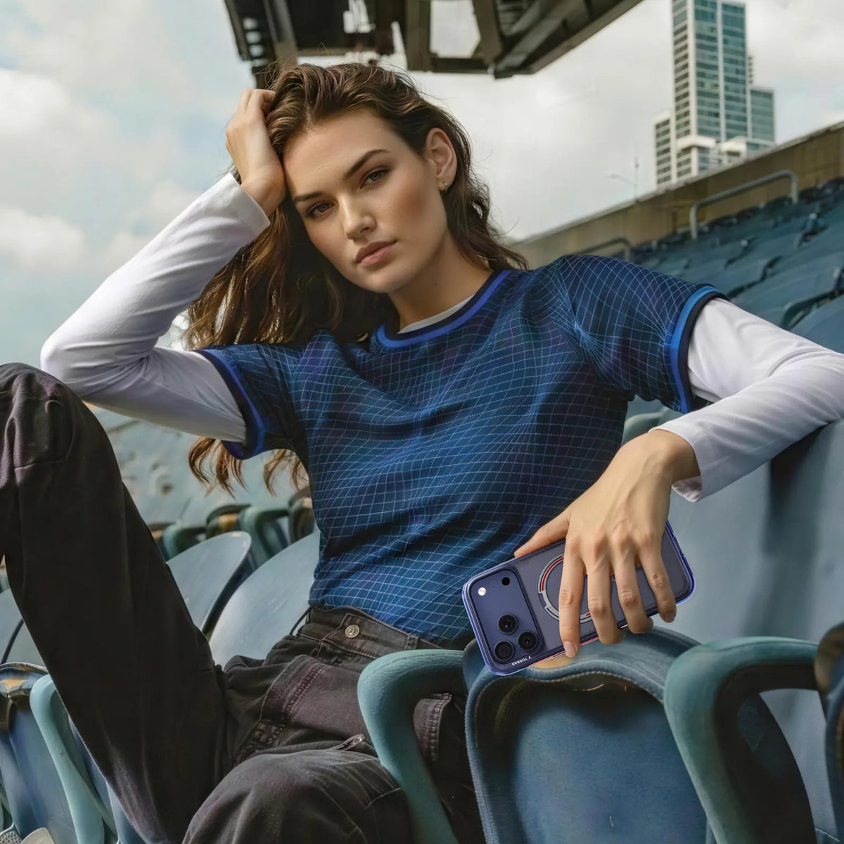 Woman in a stadium seat holding a phone in a purple TORRAS Ostand case