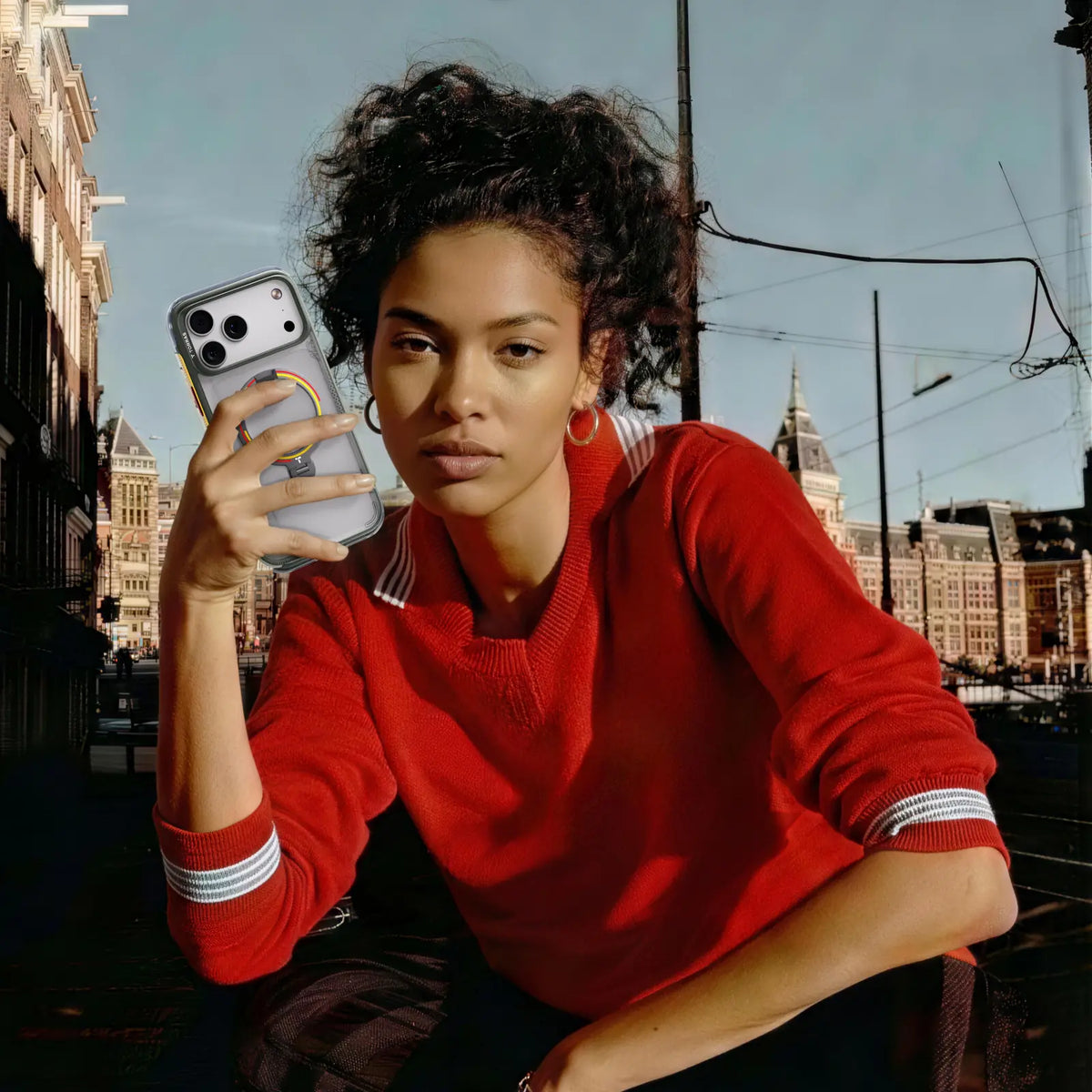 Woman on a city street holding a phone in a clear TORRAS Ostand case