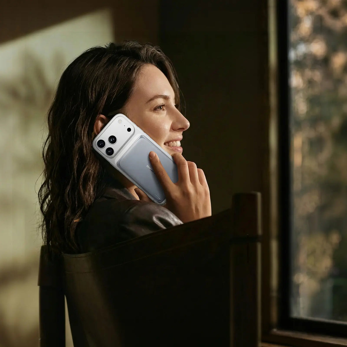 TORRAS MiniMag Pro 5k mAh slim magnetic power bank attached to iPhone, held by smiling woman.